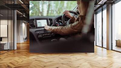 girl in car, selects application on touch screen display, navigation in car, a brown leather jacket, finding a route in summer and autumn in forest park. Right-hand drive, left-hand drive. Wall mural