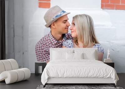 Young couple, looking at each other a bright sunny day in city of great outdoors, happy family concept, idea good relationship. Smile and smotryad  . Against background   white brick wall. Wall mural