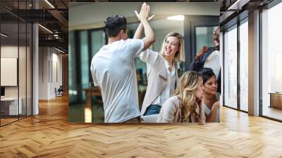 weve done it again. shot of a group of colleagues giving each other a high five while using a comput Wall mural