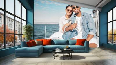 Happy couple on yacht with champagne smile and celebrate love with romantic tropical holiday travel on ocean. Dating man and woman on luxury boat on beach water or sea with wine glass for celebration Wall mural