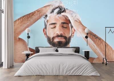 Hair care, face water splash and shower of man in studio isolated on a blue background. Water drops, shampoo and male model washing, cleaning or bathing for healthy skin, wellness or skincare hygiene Wall mural