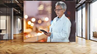 Doctor, phone and senior woman on hospital rooftop for telehealth, research or online consultation in city. Bokeh, healthcare and female medical physician with smartphone for wellness app at night Wall mural