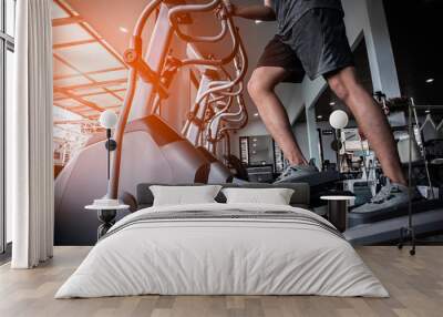 Young man working out on an elliptical trainer in gym Wall mural