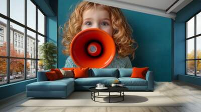 Child with a megaphone against teal background, expressive communication concept Wall mural