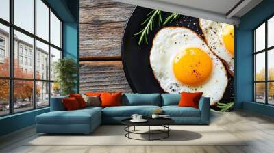 Fried eggs on a black plate with rosemary sprigs, rustic breakfast concept Wall mural