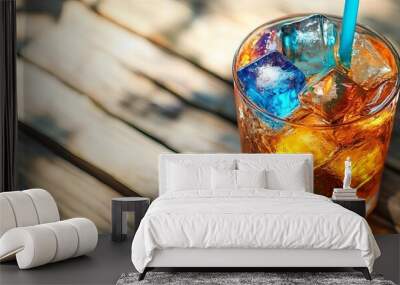 Iced cocktail with colorful ice cubes on wooden table under sunlight, refreshing summer drink concept Wall mural