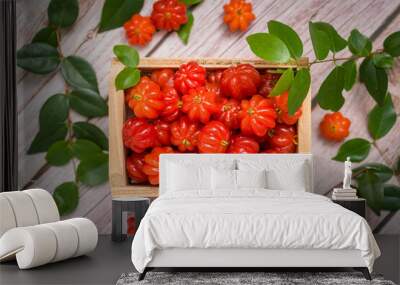 Suriname cherries in a small wooden box on a wooden surface. Wall mural