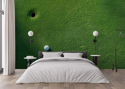 A golf ball seen from above, sitting alone on the putting green with the hole in close proximity Wall mural