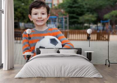 Boy holding soccer ball outdoors Wall mural