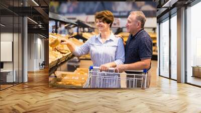 Elderly couple buys bread and baking in grocery section of supermarket Wall mural