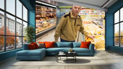 elderly man choosing cheese in supermarket Wall mural