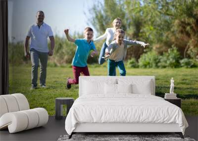 Father with mother with two children enjoy playing soccer on lawn in summer park Wall mural