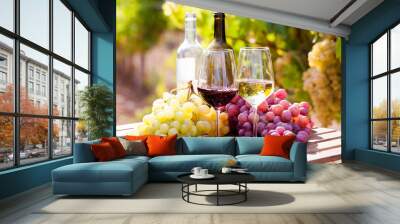 glasses of red and white wine and ripe grapes on table in vineyard Wall mural