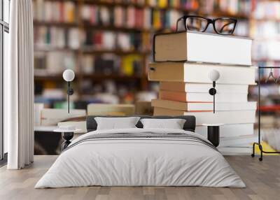 glasses on top of stack of books lying on table in bookstore Wall mural