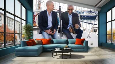 Latin American and European businessmen sit and drink beer on the yacht in seaport Wall mural