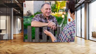 neighbors man and woman chatting near the fence in the village Wall mural