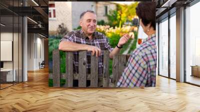 neighbors man and woman chatting near the fence in the village Wall mural