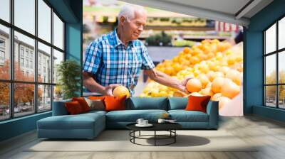 old age man choosing oranges and grapefruits in supermarket Wall mural