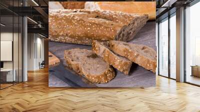 Slices of wheaten bread and knife on wooden surface Wall mural