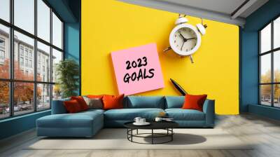 2023 goals message on pink note paper with alarm clock and pen. Planning personal or business goals for the year 2023. Wall mural