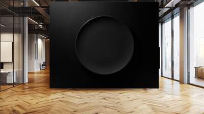 Empty round black plate on dark moody black background with copy space. Overhead view Wall mural