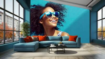 Fashion portrait of a young, stylish, happy and smiling African American woman with sunglasses on bright blue background. Wall mural