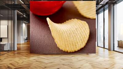 One potato chip on brown table against chili salsa sauce and potato chips background Wall mural