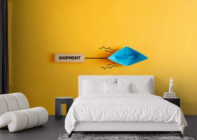 Paper boat pulls a wooden banner with the word shipment. Shipping, logistics, transportation or delivery Wall mural