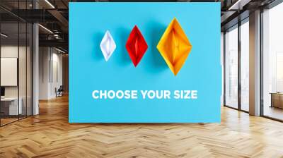 Three paper boats with different size and colors on blue background with the text choose your size Wall mural