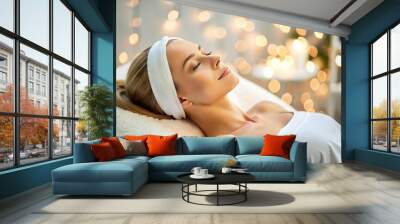 Calm woman reclines on comfortable couch, receiving gentle facial treatment with soft focus lights and serene background at a luxurious medical spa. Wall mural