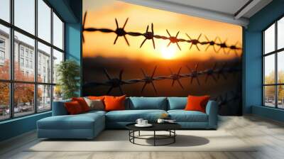 A close-up shot of barbed wire against a sunset backdrop, casting long shadows and illustrating the stark realities of border security Wall mural