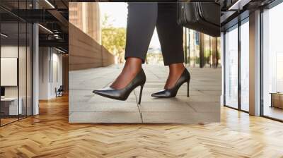 A closeup of the feet of a businesswoman in office clothing and high heels walking to work on a city street sidewalk. Wall mural