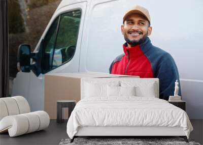 Delivery man smiling while holding parcel in front of transportation van. High quality photo Wall mural