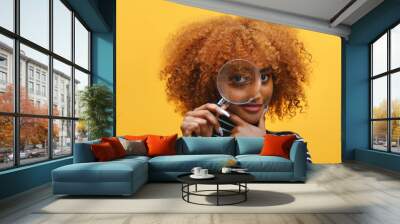 Funny young african american black woman with magnifier in hand shows eye through magnifying glass. High quality photo Wall mural