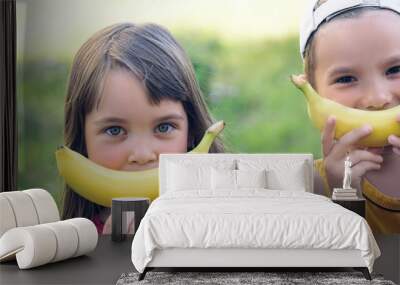 Close up portrait of a beautiful young caucasian girl and boy with banana smile on nature background. Wall mural