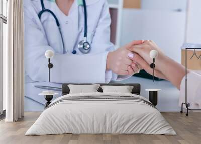 Friendly male doctor reassuring the patient and holding his hands Wall mural