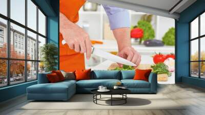 Mature man cutting vegetables in the kitchen. Wall mural