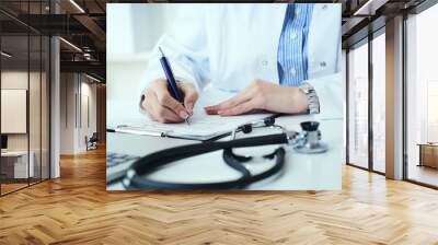 Mid section of female doctor writes prescription to patient at worktable. Panacea and life save, prescribing treatment. Wall mural