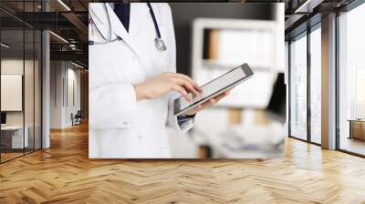 Unknown male doctor using tablet computer in clinic near his working place, closeup. Perfect medical service in hospital. Medicine and healthcare concept Wall mural