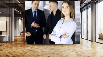 Young blonde businesswoman dressed in blouse is standing with arms crossed in a modern office. Concept of success in a business Wall mural