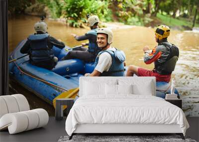 And so it begins.... High angle portrait of a handsome young man and his friends sitting in their white water raft. Wall mural