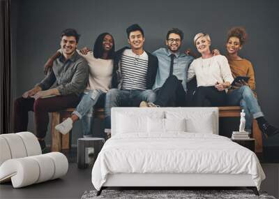 Colleagues that have become friends. Studio shot of a diverse group of creative employees embracing each other against a grey background. Wall mural