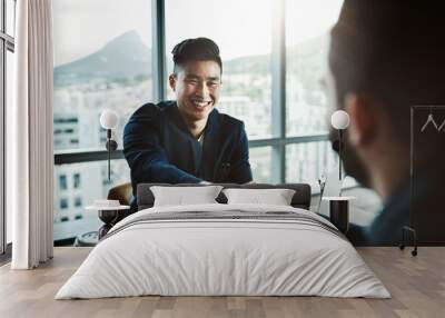 Its safe to say he made a great impression. Shot of two young businessmen shaking hands while sitting at a desk in a modern office. Wall mural