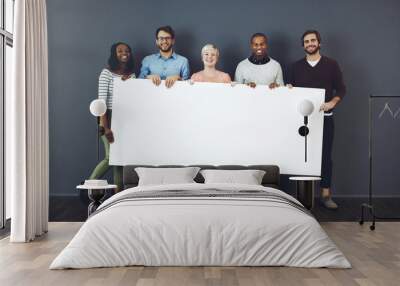 Weve got something for you.... Studio shot of a diverse group of people holding a blank placard against a gray background. Wall mural