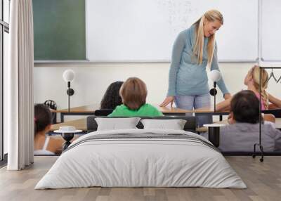 Teacher, kids and students in classroom for learning, education and math support or development at desk. Happy woman with children for teaching numbers, helping with knowledge and questions at school Wall mural