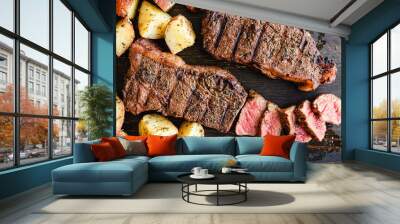 Grilled NY Strip Steak with Coffee Rub and Roasted Potatoes: Grilled New York strip steaks with roasted potatoes on a dark wood background Wall mural