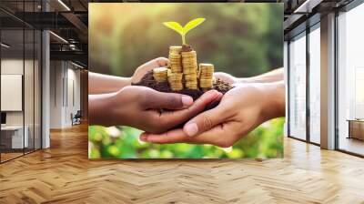 green economic development concept, two people hand holding a stack of gold coin with soil and a sprout of green plant come out in the top with bokeh blurry background Wall mural