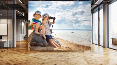 Babygirl and babyboy sitting on the beach Wall mural