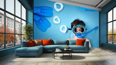 Child lying on blue blanket with swimming mask and flippers Wall mural