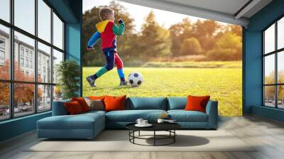 Child playing football on the field with gates. Wall mural